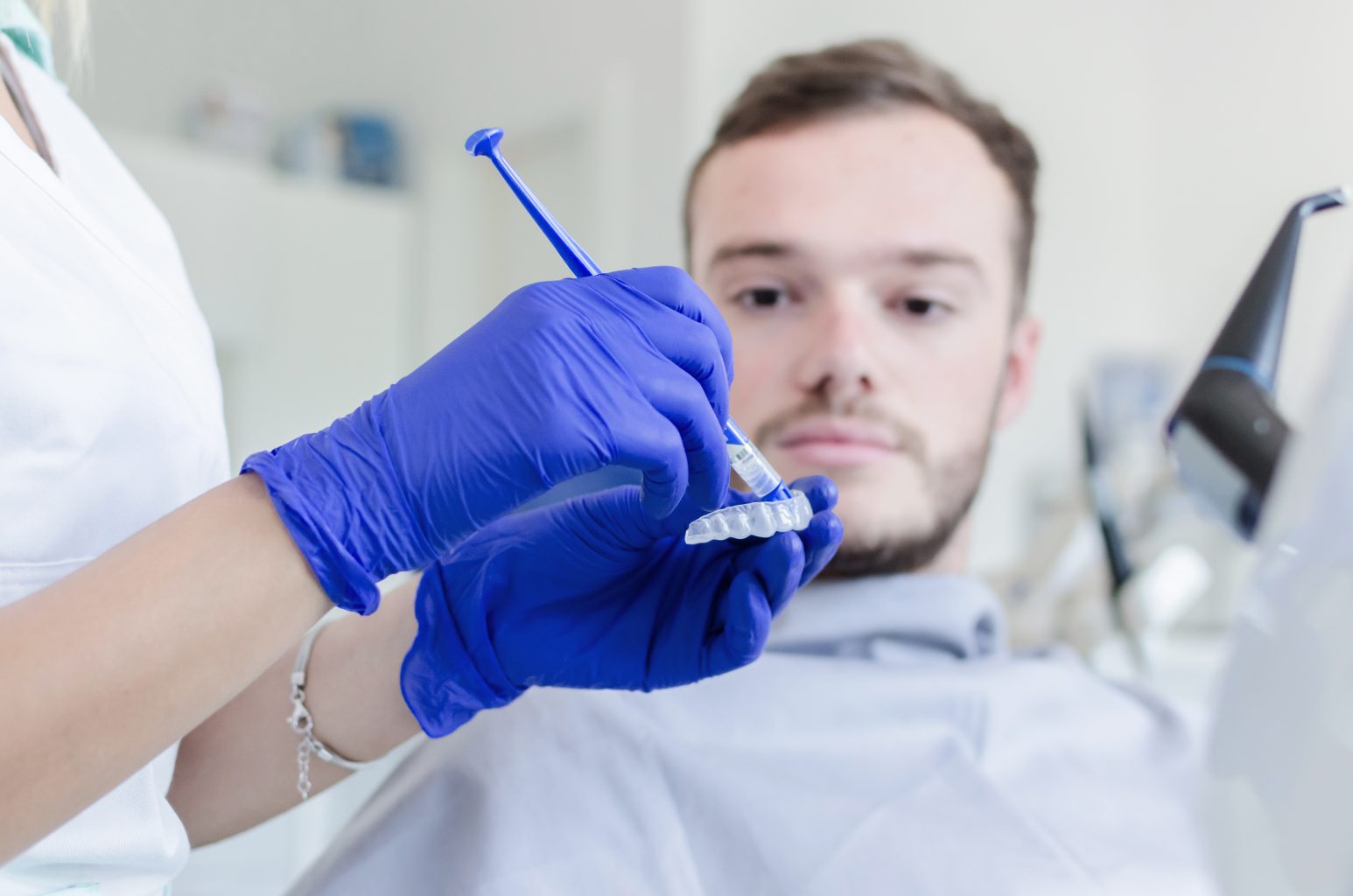 Man Whitening Teeth In Dental Office